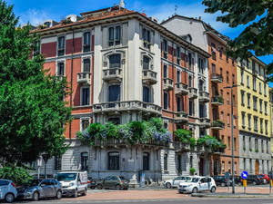 色彩繽紛的歷史公寓建築，設有陽台，汽車停放在陽光明媚的城市街道上。 — 城市景觀 壁紙