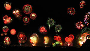 色彩繽紛的煙火以紅色、綠色和金色光芒照亮夜空。 — 慶祝 壁紙