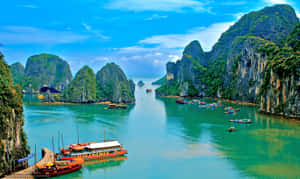 高聳的綠色島嶼從碧綠的海水中升起，碼頭旁停靠著船隻。 — 越南 壁紙