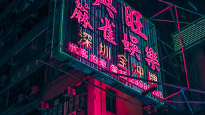 霓虹燈在夜晚用粉紅色和藍綠色的燈光照亮城市建築。 — 霓虹燈 壁紙
