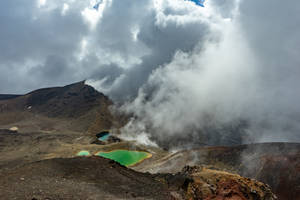 火山景觀，有冒著蒸汽的溫泉和戲劇性的雲彩。