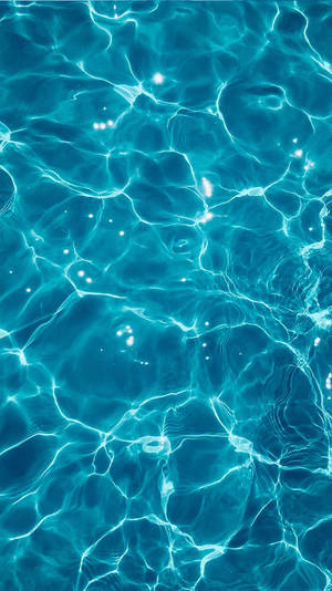 陽光在漣漪的藍綠色泳池水上舞動，形成明亮發光的圖案。 — 美麗的藍色 壁紙