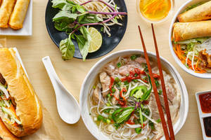 越南菜餚，河粉、春捲和越南法包在木桌上。 — 貴賓狗 壁紙