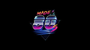 在黑色背景上帶有霓虹漸變和幾何形狀的醒目復古文字「Made in the 80s」。 — 80年代美學 壁紙