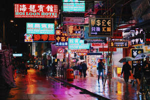 夜雨中的繁華霓虹城市街道，行人撐傘。 — 香港 壁紙