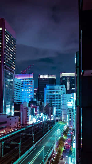 霓虹燈照亮的夜間城市天際線，發光的建築物和潮濕的街道。 — 東京 壁紙