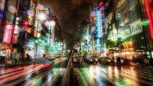 雨濕的東京街道在夜晚閃爍著霓虹招牌和模糊的車燈。 — 東京 壁紙