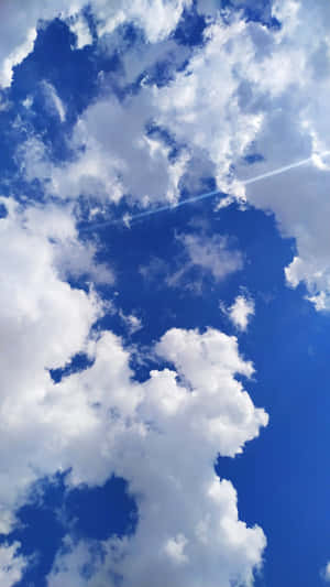 鮮豔的藍天，有蓬鬆的白雲和一道陽光照射。 — 美學天空 壁紙