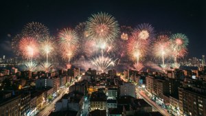 煙火在夜間城市上空綻放，下方交通燈光形成條紋。 — 新年 壁紙