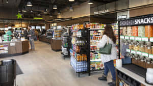 購物者在現代雜貨店瀏覽零食貨架和「The Cellar」區域。 — 7-ELEVEN 壁紙