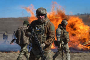 全副武裝的士兵穿過田野前進，身後有大火。 — 戰爭動圖 壁紙