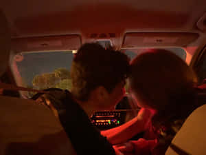 兩人在夜晚的車內，紅色燈光下緊靠而坐。 — 夜晚 壁紙