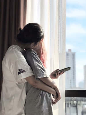 兩人在俯瞰城市的窗邊擁抱。 — 女同志 GIF 壁紙