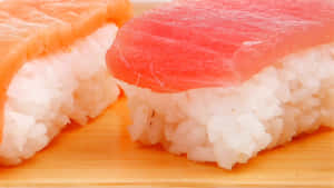兩件壽司，上面有鮪魚和鮭魚，放在竹蓆上的飯上。 — 壽司 壁紙