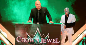 兩位WWE摔角手在Crown Jewel活動頒獎台上，一位戴面具，一位沒戴面具。 — 終極格鬥冠軍賽 壁紙