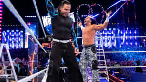 兩位摔角手在摔角擂台上與梯子和歡呼的粉絲一起慶祝勝利。 — WWE GIF 壁紙