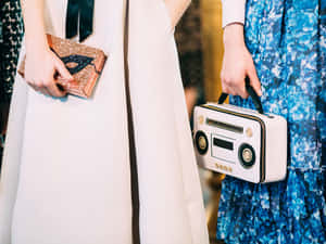 兩位女士在晚間時尚活動中手持獨特手袋。 — Kate spade 壁紙