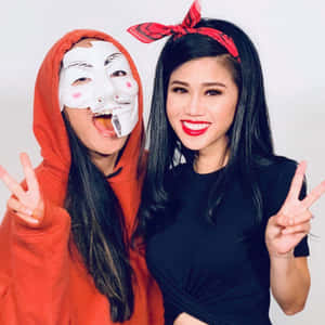 兩位女性比出和平手勢，一位穿紅色連帽衫戴面具，另一位穿黑色上衣戴紅色頭巾。 — 間諜忍者 壁紙
