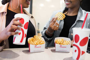 兩位女性在桌上對著Chick-fil-A的格子薯條和飲料大笑。 — 薯條 壁紙