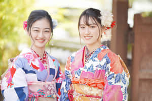 兩位穿著彩色和服的年輕女性在明亮的陽光下微笑著在戶外。 — 日本武士 壁紙