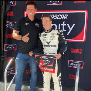 兩位男士在NASCAR Xfinity Series頒獎台上，一位穿著賽車服拿著獎項，另一位豎起大拇指。 — 極限運動 壁紙
