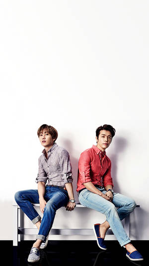 兩位身穿休閒服的年輕男子坐在白色牆壁前的長椅上。 — Super Junior 壁紙