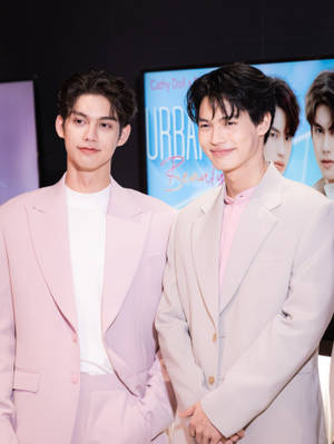 兩位身穿粉紅色西裝的男士在宣傳活動中微笑。 — 美學粉色GIF 壁紙