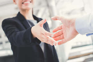 兩位專業人士在明亮的辦公室中微笑握手。 — 手牽手 壁紙