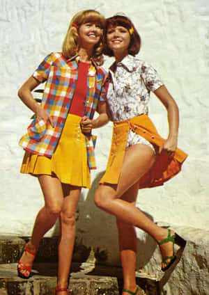 兩位身穿色彩繽紛1960年代服裝的女士在石階上微笑。 — 70年代動圖 壁紙