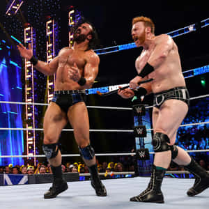 擂台上兩位摔角手，一人手持椅子，另一人向觀眾做手勢。 — WWE GIF 壁紙
