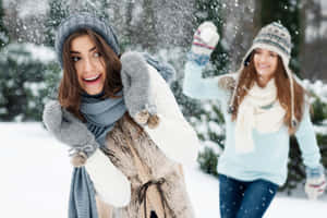 兩位女性在雪地森林中笑著並拋雪。 — 可愛的雪 壁紙