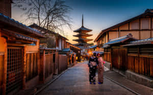 兩位身穿和服的女士在日落時分沿著傳統日本小巷走向寶塔。 — 日本 壁紙