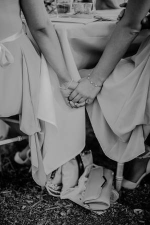 兩位伴娘在婚禮桌上握手，地上有鞋子和手拿包。 — 婚紗 壁紙