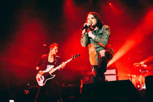 樂隊在紅色燈光下與歌手和低音吉他手現場表演。 — MacBook Pro 壁紙