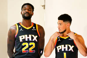 兩位鳳凰城太陽隊籃球運動員身穿隊服在室內擺姿勢。 — Devin Booker 壁紙