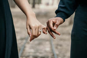 兩個人在火車軌道上牽手，訂婚戒指可見。 — 情侶 壁紙