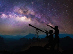 兩個孩子晚上在山上用望遠鏡觀察銀河。 — 夜空 壁紙