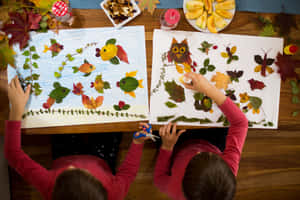 孩子們在秋季主題的桌子上用紙創作樹葉藝術。 — 秋季美學 壁紙