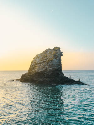 兩個人在岩石島上日落時分，平靜的海水 — 海洋 壁紙