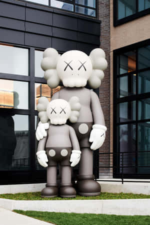 兩個大型灰色KAWS Companion雕像一起站在現代建築外。 — 榮耀MagicPad 3 Pro 壁紙