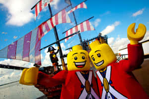 兩個LEGO海盜角色從一艘帶有彩色帆的船上揮手。 — 樂高 壁紙