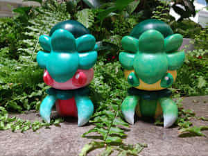 兩個上色的 Bulbasaur 公仔在石頭表面的蕨類植物之間。 — 卡通 壁紙