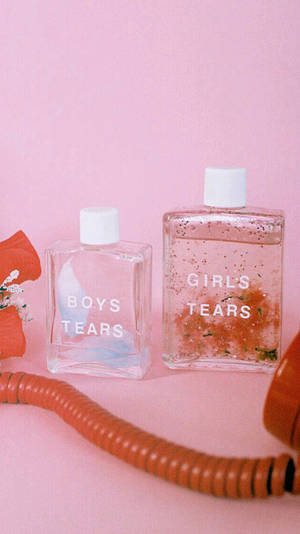 兩個香水瓶，標有 boys tears 和 girls tears，放在粉紅色背景上，配有一條橙色電話線。 — 美學粉色GIF 壁紙