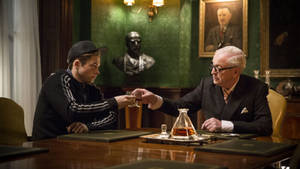 兩個男人在一個正式的書房裡碰杯，有綠色牆壁和肖像畫。