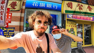兩個男人在繁忙的街道上自拍，背景有中式商店和霓虹招牌。 — 不思議遊戯 壁紙