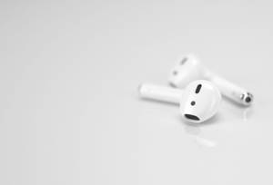 兩個白色無線耳塞在一個反射的白色表面上。 — AirPods 壁紙