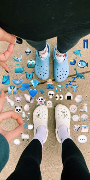兩個穿著Crocs的人被人行道上的表情符號貼紙包圍。 — Crocs 壁紙