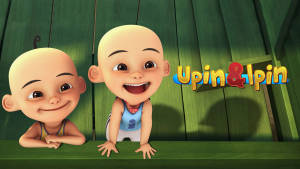 兩個動畫光頭男孩在帶有Upin & Ipin標誌的綠色木柵欄後面微笑。 — 可愛卡通 壁紙