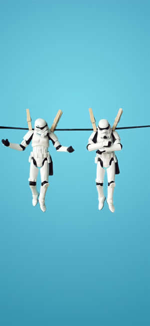 兩個風暴兵玩具人偶掛在曬衣繩上，背景為藍色。 — Pixel 8a 壁紙