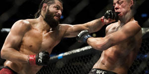 兩名男性拳手在UFC八角鐵籠內互相出拳。 — 午夜 壁紙